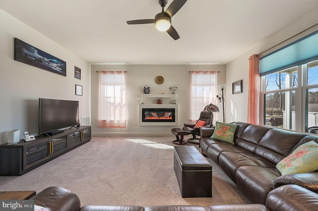 carpeted living area with ceiling fan and a glass covered fireplace