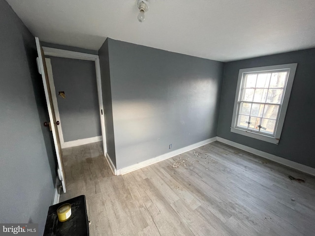 spare room with baseboards and wood finished floors