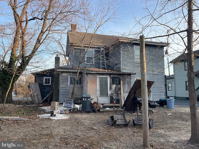 back of property with entry steps and a chimney