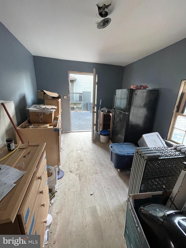 bedroom featuring light wood finished floors and freestanding refrigerator