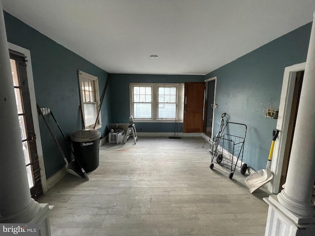 interior space with baseboards, light wood-type flooring, and ornate columns