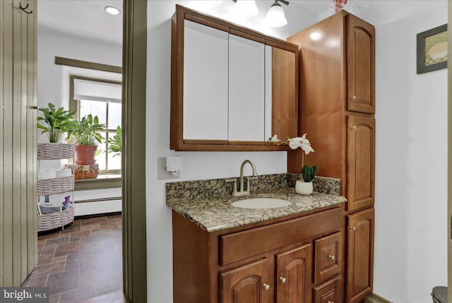 bathroom with stone tile floors, vanity, and a baseboard heating unit