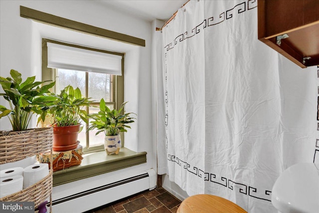 bathroom featuring a shower with shower curtain, stone tile floors, and baseboard heating