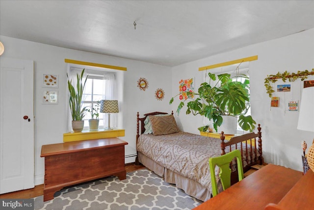 bedroom featuring a baseboard heating unit and wood finished floors