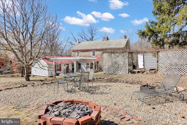 back of property featuring a patio and an outdoor fire pit