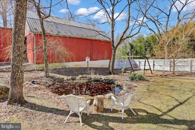 view of yard with a barn, an outdoor structure, and fence