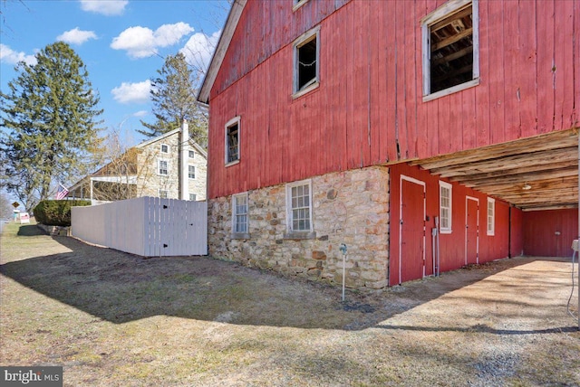 view of side of home featuring stone siding and an outbuilding