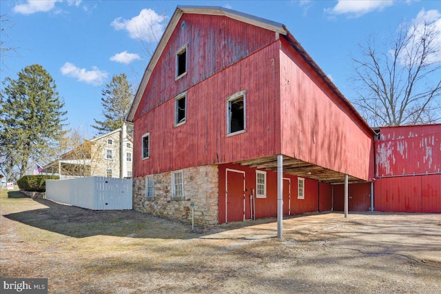 view of side of property featuring stone siding, a barn, and an outbuilding