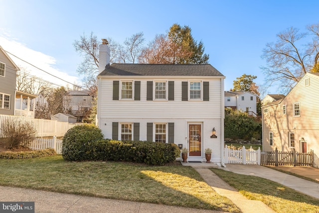 view of front facade featuring a chimney, a front yard, and fence