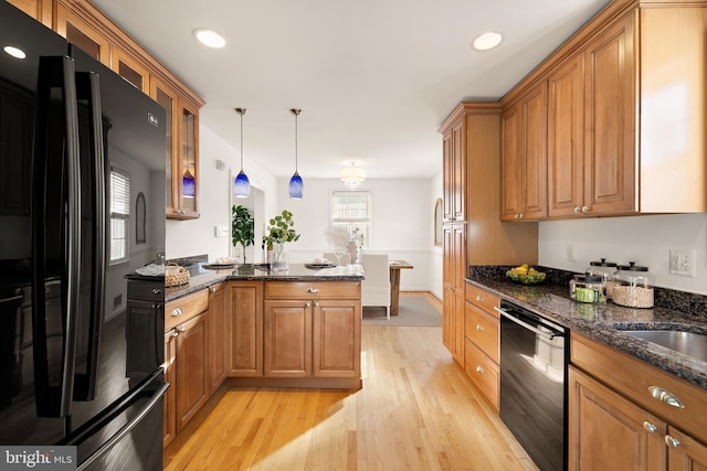 kitchen featuring brown cabinetry, light wood-style floors, glass insert cabinets, a peninsula, and black appliances