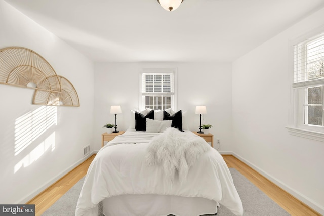 bedroom featuring light wood-type flooring, visible vents, and baseboards