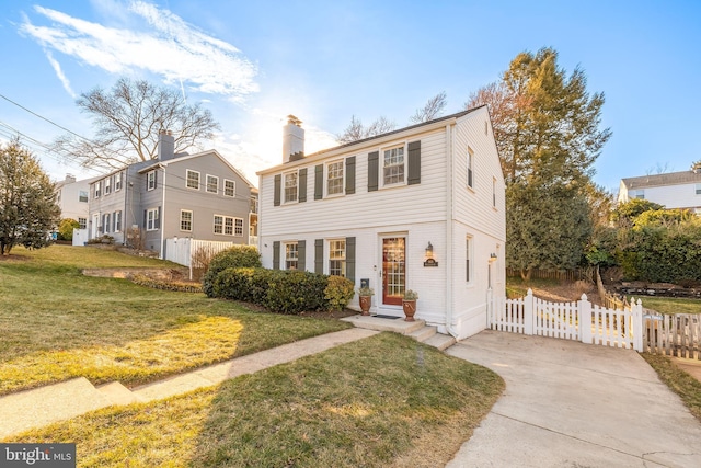 view of front of property with entry steps, fence, driveway, a front lawn, and a chimney