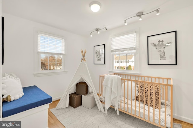 bedroom featuring wood finished floors, rail lighting, and baseboards