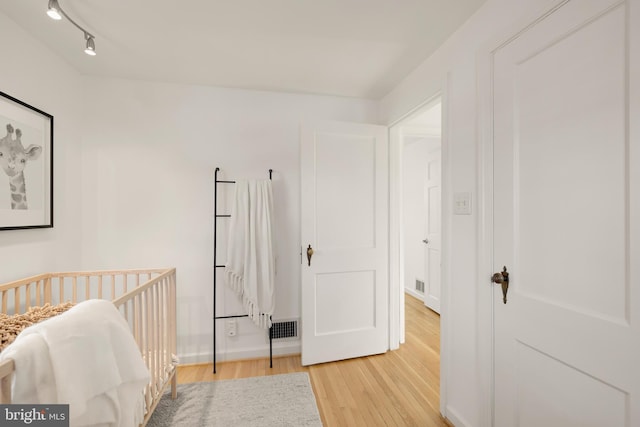 bedroom with rail lighting, visible vents, and light wood-style flooring