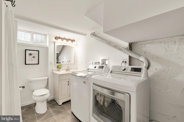 laundry area with a sink, laundry area, washer and dryer, and concrete block wall