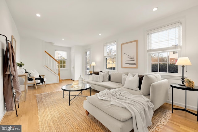 living room featuring light wood-style flooring, recessed lighting, and stairway