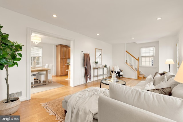 living area featuring recessed lighting, visible vents, baseboards, stairway, and light wood finished floors