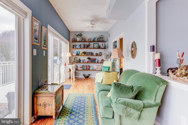 living area with plenty of natural light, a textured ceiling, a ceiling fan, and wood finished floors