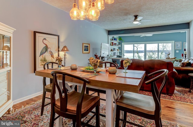 dining area with light wood-style flooring, baseboards, ceiling fan, and a textured ceiling