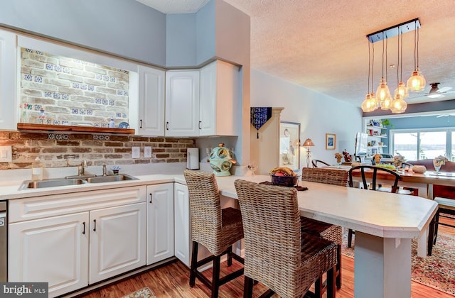 kitchen featuring a breakfast bar, a peninsula, light countertops, a textured ceiling, and a sink