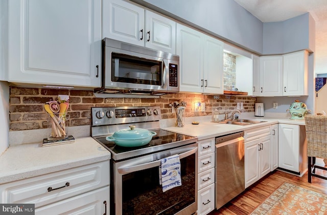 kitchen featuring white cabinets, light wood-type flooring, stainless steel appliances, and light countertops