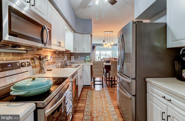 kitchen with stainless steel appliances, light countertops, white cabinets, and light wood-style floors