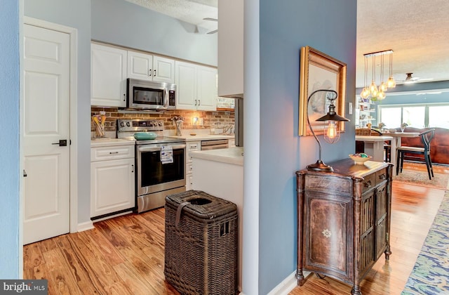 kitchen with appliances with stainless steel finishes, light wood-style floors, light countertops, and ceiling fan