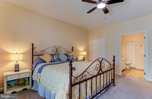 carpeted bedroom featuring ceiling fan, a closet, ensuite bathroom, and baseboards