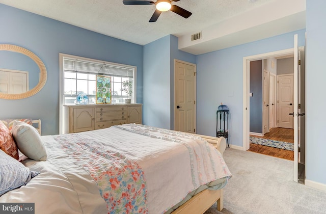 bedroom featuring a textured ceiling, carpet flooring, visible vents, and baseboards