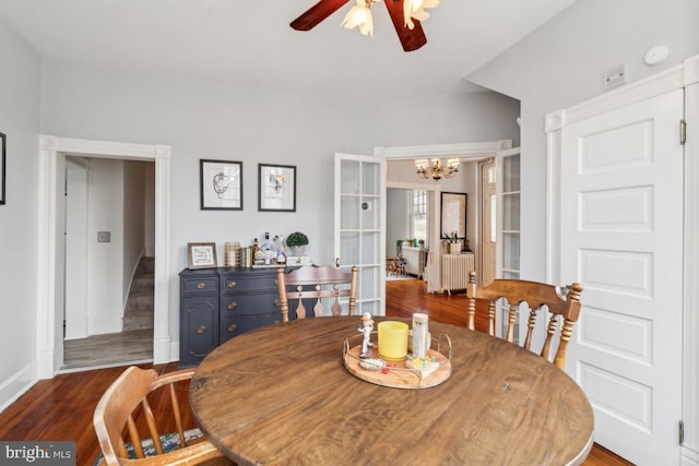 dining space featuring stairs, radiator, dark wood-type flooring, baseboards, and ceiling fan with notable chandelier