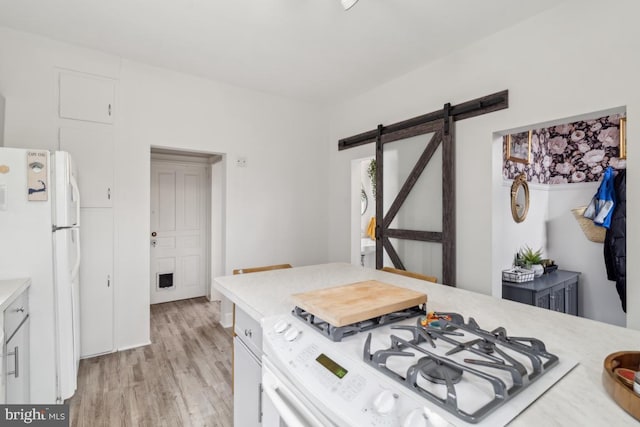 kitchen featuring white appliances, light countertops, light wood finished floors, and a barn door