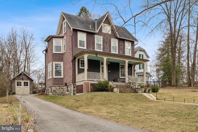 view of front of home featuring a porch, an outbuilding, a garage, and a front lawn