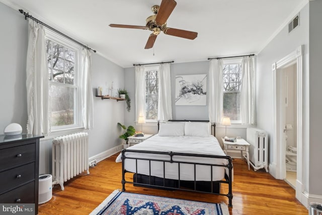 bedroom with light wood-type flooring, radiator, visible vents, and baseboards