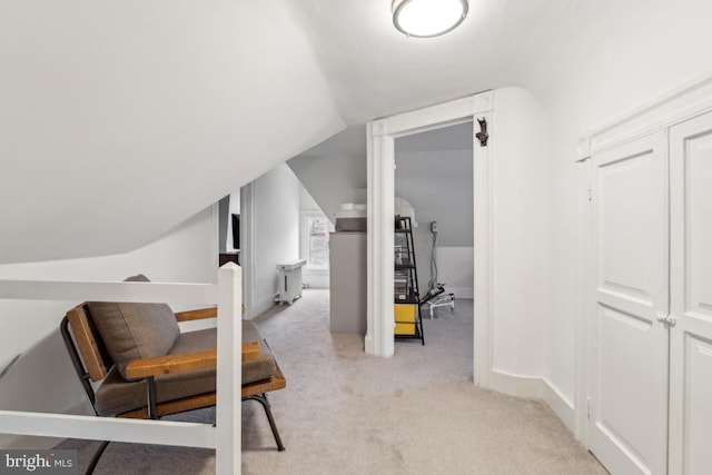 hallway featuring light carpet, baseboards, and lofted ceiling