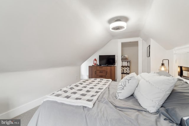 carpeted bedroom with baseboards and vaulted ceiling