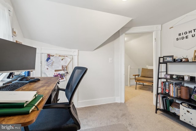 carpeted office space featuring vaulted ceiling and baseboards