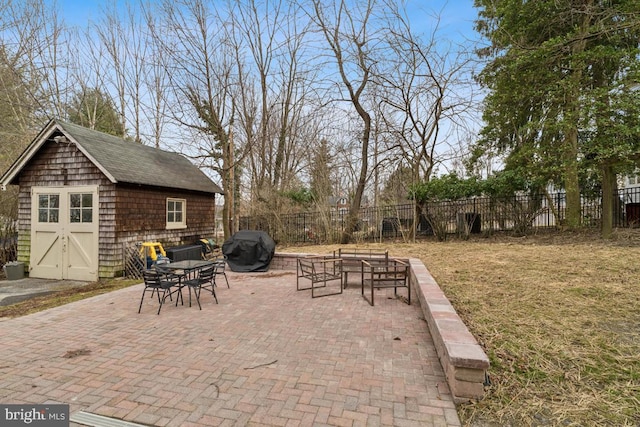 view of patio with an outbuilding, fence, grilling area, and a storage unit