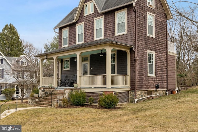 shingle-style home featuring covered porch, a front lawn, and roof with shingles