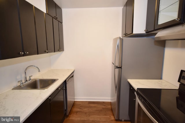 kitchen featuring light stone counters, a sink, baseboards, appliances with stainless steel finishes, and dark wood-style floors