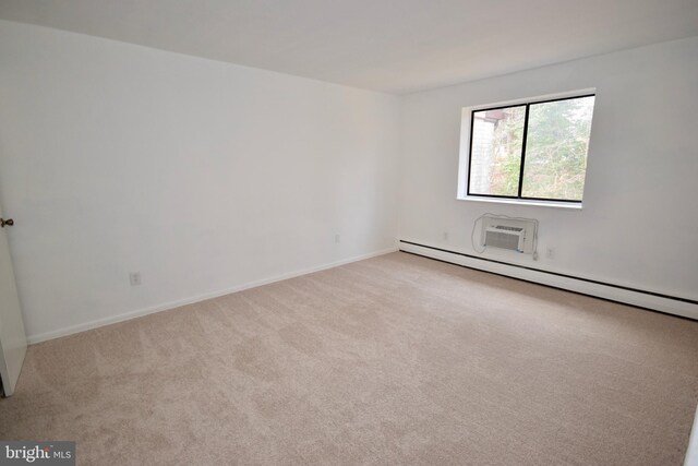 carpeted empty room featuring a baseboard heating unit, a wall mounted air conditioner, and baseboards