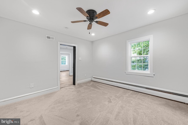 empty room featuring a baseboard radiator, carpet flooring, visible vents, and a healthy amount of sunlight