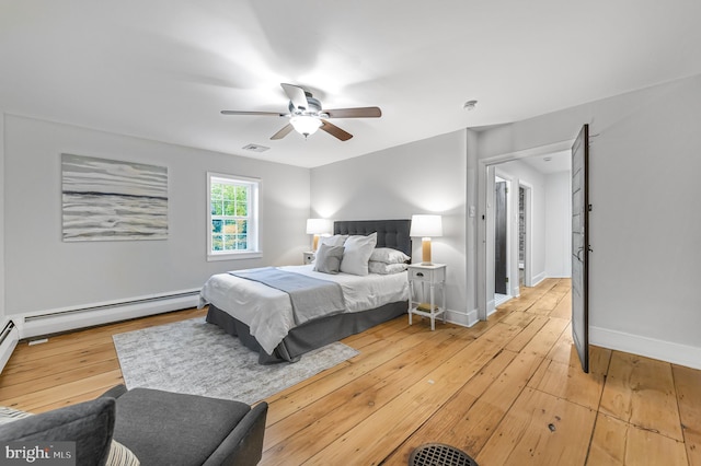 bedroom with light wood finished floors, visible vents, baseboard heating, a ceiling fan, and baseboards