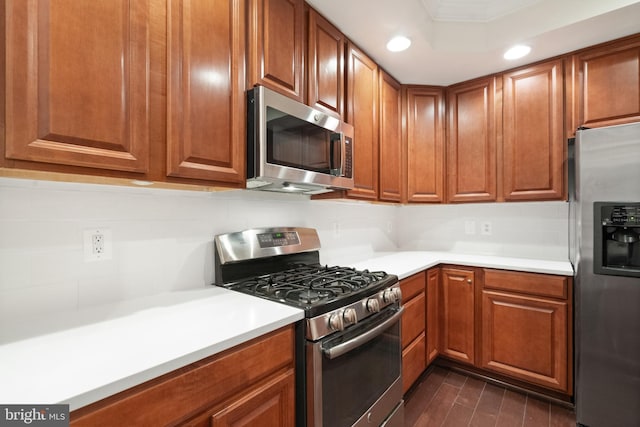 kitchen featuring light countertops, brown cabinetry, dark wood-type flooring, and stainless steel appliances