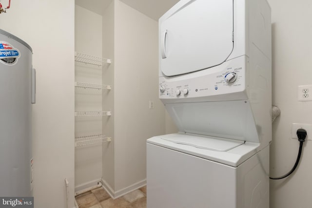 clothes washing area featuring water heater, laundry area, stacked washer / drying machine, and baseboards