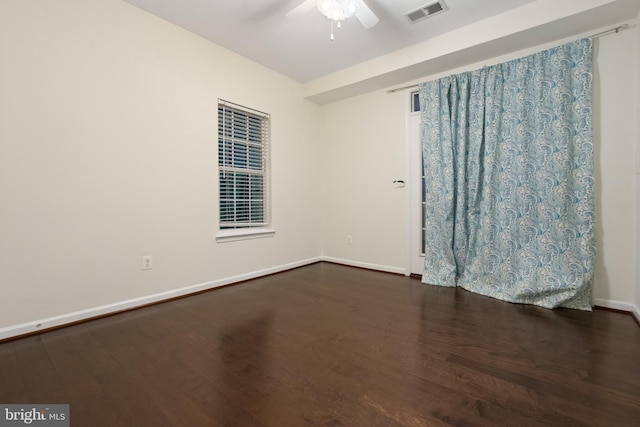 empty room featuring dark wood finished floors, baseboards, visible vents, and ceiling fan