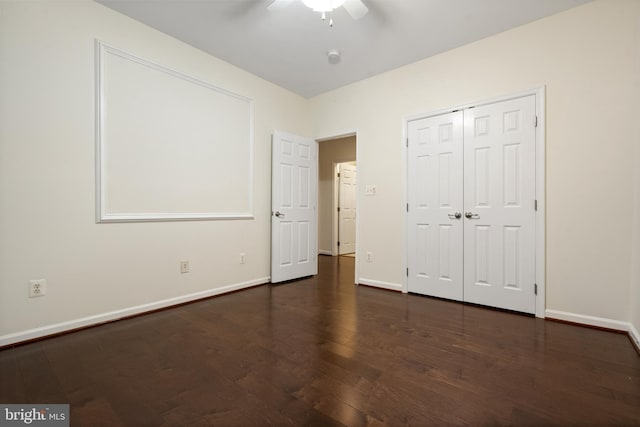 unfurnished bedroom with a closet, a ceiling fan, dark wood-type flooring, and baseboards