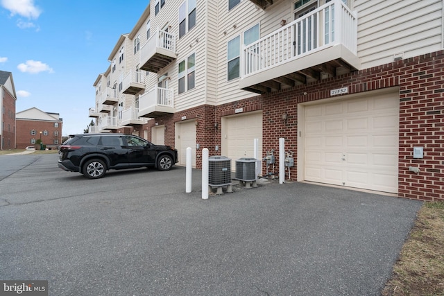 exterior space with cooling unit, a garage, and driveway