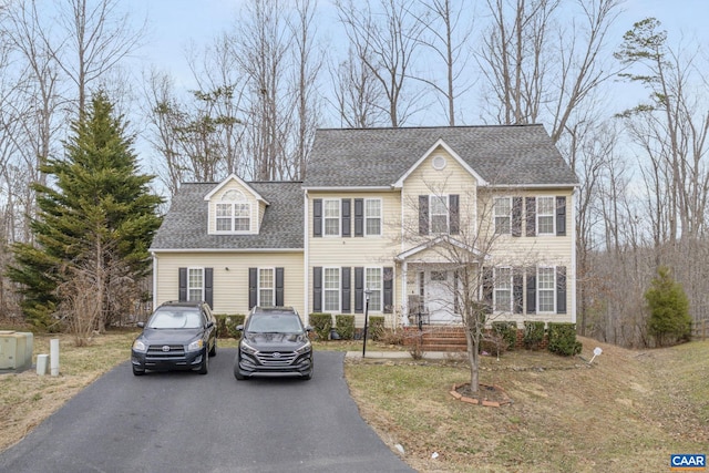 colonial inspired home with driveway and roof with shingles