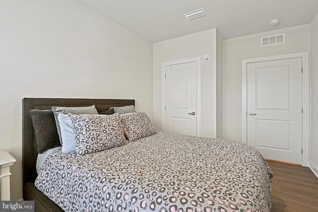 bedroom featuring lofted ceiling, visible vents, and wood finished floors