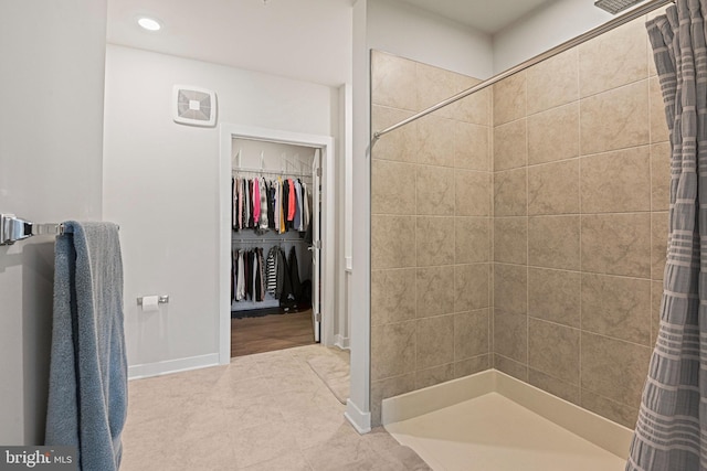 bathroom featuring a stall shower, a spacious closet, baseboards, and recessed lighting